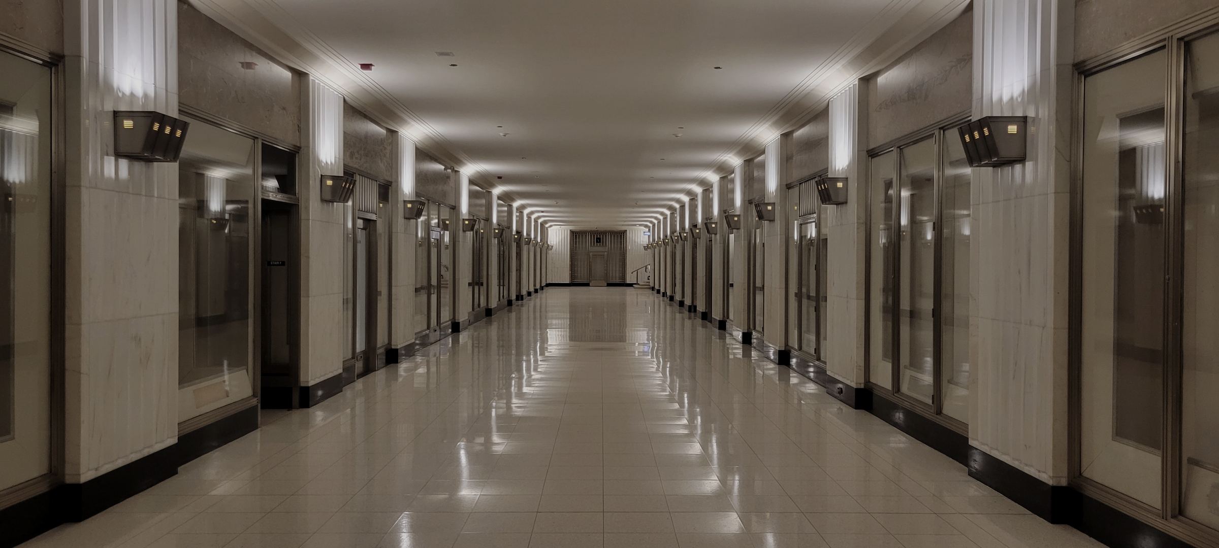 The lower arcade of the Field Building, a long marble corridor lit by bronze sconces